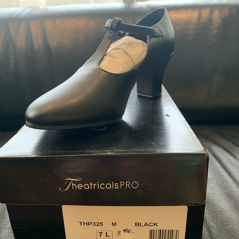 Black T-strap character shows. 2 inch heel. New. Size 7.